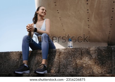 Young fitness woman resting after workout session on sunny morning. Royalty-Free Stock Photo #2316236875