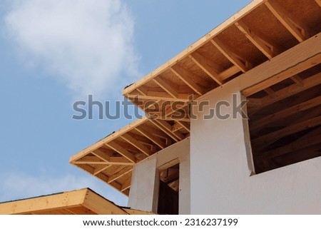 There are wooden beams rafters planks along corner of house that are attached to eaves Royalty-Free Stock Photo #2316237199