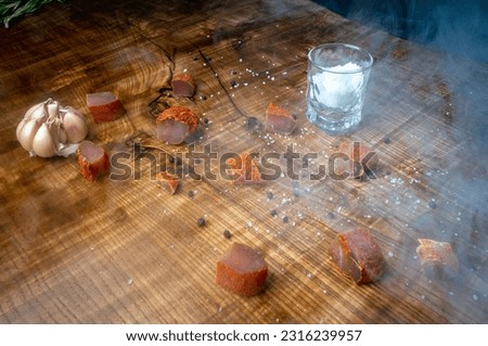 Pieces of meat laid out on the table with a glass of salt in the smoke