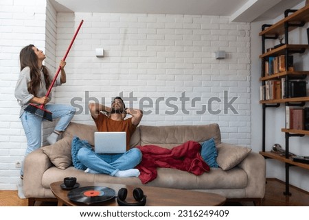 Young couple stares at the ceiling and yells because a neighbor upstairs is having a party with loud music or renovating an apartment and workers are drilling with heavy tools. Noise pollution concept Royalty-Free Stock Photo #2316249409