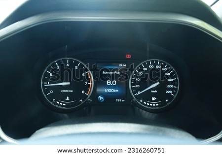A picture with noise effect of car dashboard with information of average fuel consumption for a car.
