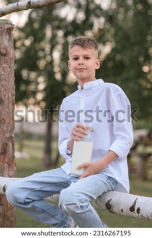 Portrait of a joyful boy on a farm drinking milk. Time relax. Talk and look away. Light sunny day. food and drink concept, healthy food. Little boy in a haystack drinking milk
