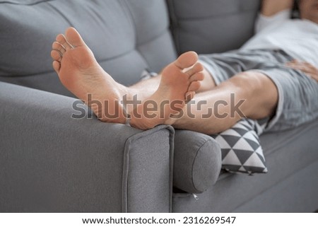 Tired man resting after work at home, male feet, body care concept at home interior Royalty-Free Stock Photo #2316269547