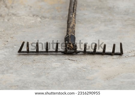 Old metal rake for cleaning leaves and grass, close-up.Yard area cleaning. Royalty-Free Stock Photo #2316290955