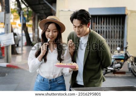  Asian couple traveler wearing a casual wear and hat in relationship buying a dessert snack on street food market in the evening. Backpacker traveling in Bangkok, Thailand. Royalty-Free Stock Photo #2316295801