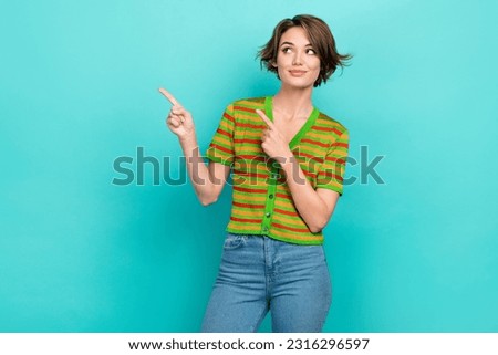 Photo of sweet cheerful woman dressed striped t-shirt looking pointing two fingers empty space isolated turquoise color background