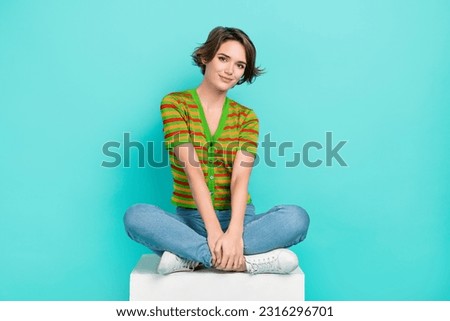 Full size photo of lovely peaceful girl sitting cube podium isolated on bright teal color background