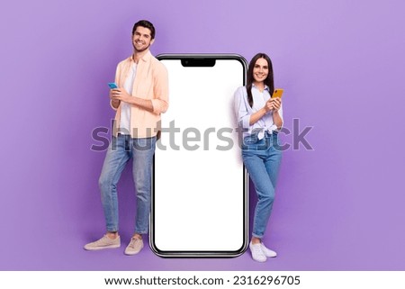 Full size portrait of two nice cheerful people use smart phone big empty space poster isolated on purple color background Royalty-Free Stock Photo #2316296705