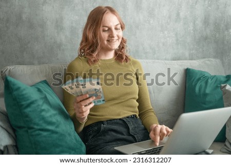Focused young woman holding money in her hands, calculating family budget, trying to save some money to buy new bicycle to her son, having stressed and concentrated look. High quality photo