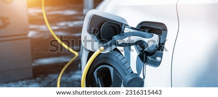 Close-up modern electric plug-in hybrid car parked near fast charger charging station point in center street old European city. Eco friendly green energy vehicle. Zero emission transport technology Royalty-Free Stock Photo #2316315443