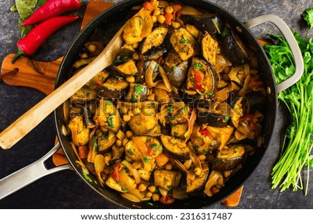 Vegan Roasted Eggplant and Chickpea Curry Served in a Skillet: Aubergine curry with garbanzo beans, tomatoes, onions and cilantro Royalty-Free Stock Photo #2316317487