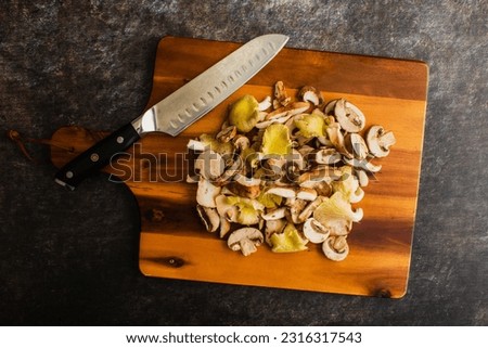 Sliced Wild Mushrooms with a Chef's Knife on a Wooden Cutting Board: Prepped oyster, shiitake, and crimini mushrooms piled up on a chopping board Royalty-Free Stock Photo #2316317543