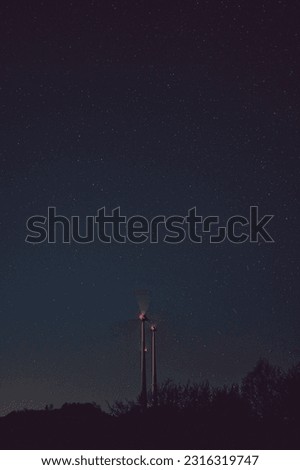 A vertical shot of the wind turbines captured at night against the starry sky