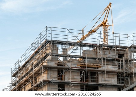 crane over construction site with shells with scaffolding against blue sky