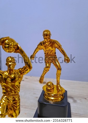 A closeup picture of golden basketball player and football player trophies
