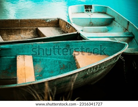 Beautiful old fishing boats float near the shore on the blue surface of the lake on a clear summer day. Recreation and fishing.
