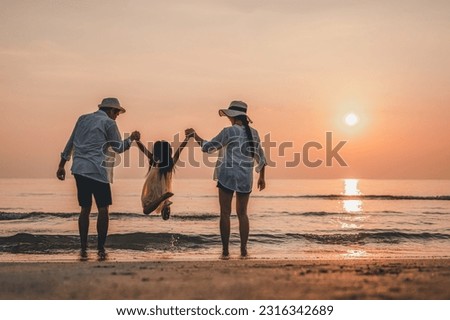 Happy Asian family jumping together on the beach on vacation. Family silhouette holding hands enjoying sunset on the beach. Happy family travel and vacation concept.