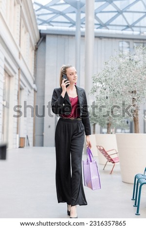 woman using mobile phone looks at camera standing in the street.