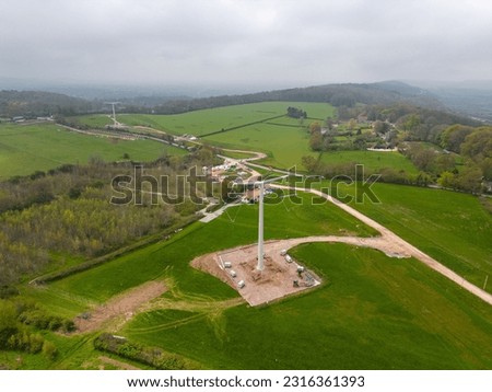 An aerial view of a vast expanse of land with T-pylons to connect a nuclear reactor at Hinkley Point Royalty-Free Stock Photo #2316361393