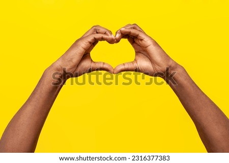 gesture of love, hands of african american man show heart on yellow isolated background, guy makes symbol of romance with his hands, close-up