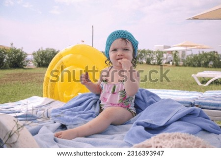 One year old girl sitting on sunbed