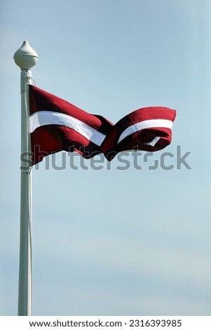 the red and white national flag flies high on the mast