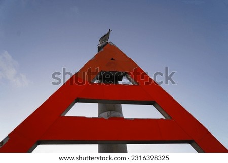 A seagull standing on a red triangle sign