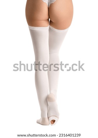 Legs in white compression stockings on a white background, thromboembolism prevention, treatment of varicose veins, venous therapy, compression stockings for surgery.