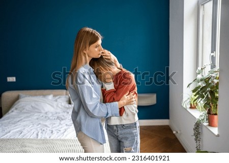 Mother hugging comforting upset crying teenage daughter at home, single mom showing love support to sad worried child, embracing and supporting teen girl, helping to cope with first love heartbreak Royalty-Free Stock Photo #2316401921