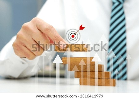 Hand holding a wooden block the top one with target icon symbol and arrow pointing up show growth business. Business strategy and target of business.