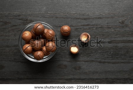 Macadamia nuts in bowl on a wooden background