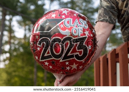 A man holding colorful graduation helium balloon in his hands