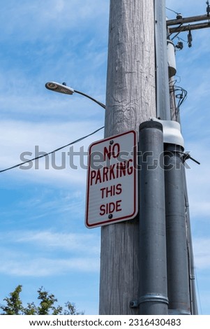 A no parking this side sign on telephone pole with a LED street light behind it in Beemus Point, New York, USA on a sunny spring day