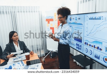Young african businesswoman presenting data analysis dashboard on TV screen in modern meeting. Business presentation with group of business people in conference room. Concord Royalty-Free Stock Photo #2316434059