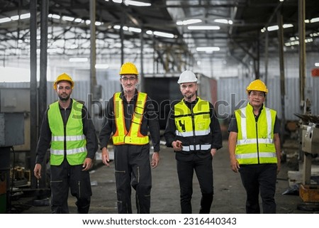Engineers and technicians and workers, working together as a team, walking like an executive inside an industrial warehouse.