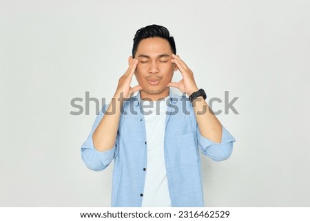 Portrait of handsome young Asian man in casual clothes massaging temples with closed eyes, trying to calm down isolated on white background Royalty-Free Stock Photo #2316462529