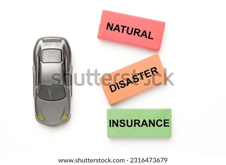 A picture of car diorama with natural disaster insurance word at wooden block on white background.