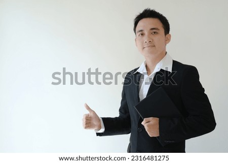 Young Asian business man holding a tablet device and giving thumb up while looking to the camera
