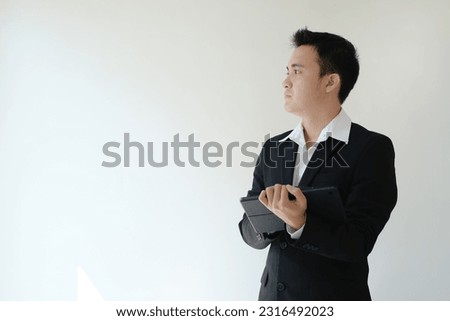 Young Asian business man holding a tablet device and looking to his right side