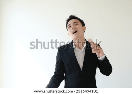 Young Asian business man with happy face expression fanning himself with Indonesian money