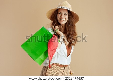 Beach vacation. happy modern woman in white blouse and shorts against beige background with bikini and summer hat.