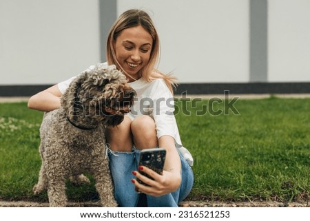 Teenage girl is taking a selfie with her adorable happy dog outside.