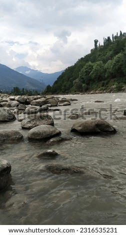 Calm River with beautiful mountain and stones, greenery, sky and clouds