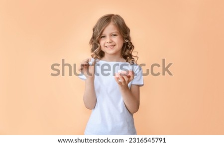 A child holds a wooden toy model of a human jaw close-up and a wooden tooth in the other hand on a beige background. Children's dentistry. Healthy baby milk teeth and gums. copy space