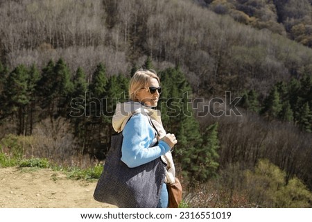 Blonde tourist enjoys vacation on mountains. Woman makes photos of mountain hills