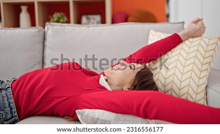 Young hispanic woman lying on sofa relaxing at home