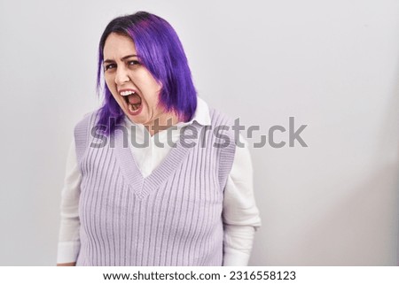 Plus size woman wit purple hair standing over white background angry and mad screaming frustrated and furious, shouting with anger. rage and aggressive concept. 