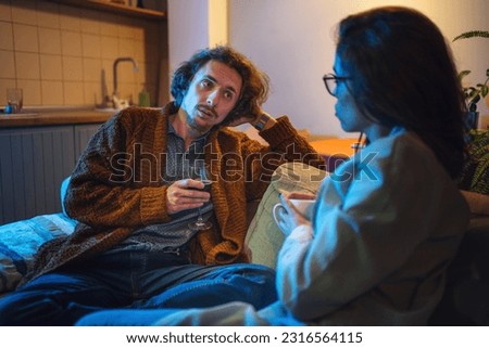Young couple spends time in evening at home on couch. Husband and wife discuss business and relationship problems Royalty-Free Stock Photo #2316564115