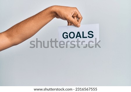 Hand of caucasian man holding paper with goals word over isolated white background