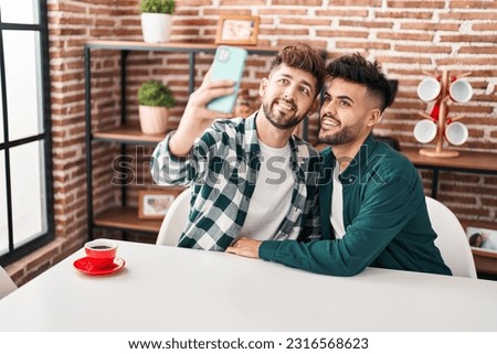 Young couple make selfie by the smartphone sitting on table at home